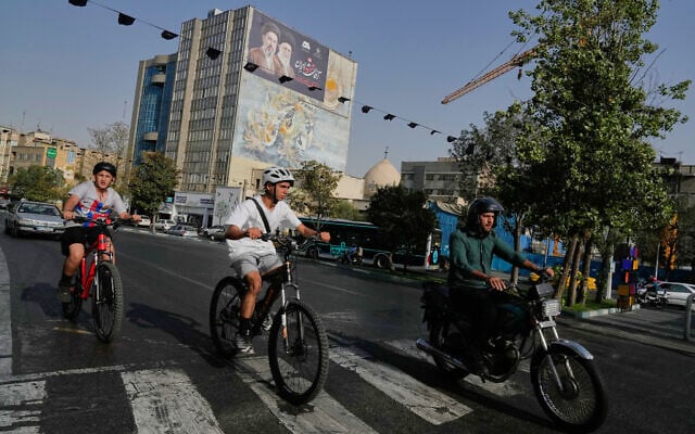 A man rides on his motorbike as boys ride their bicycles in downtown Tehran, Iran, July 22, 2026. (AP Photo/Vahid Salemi)