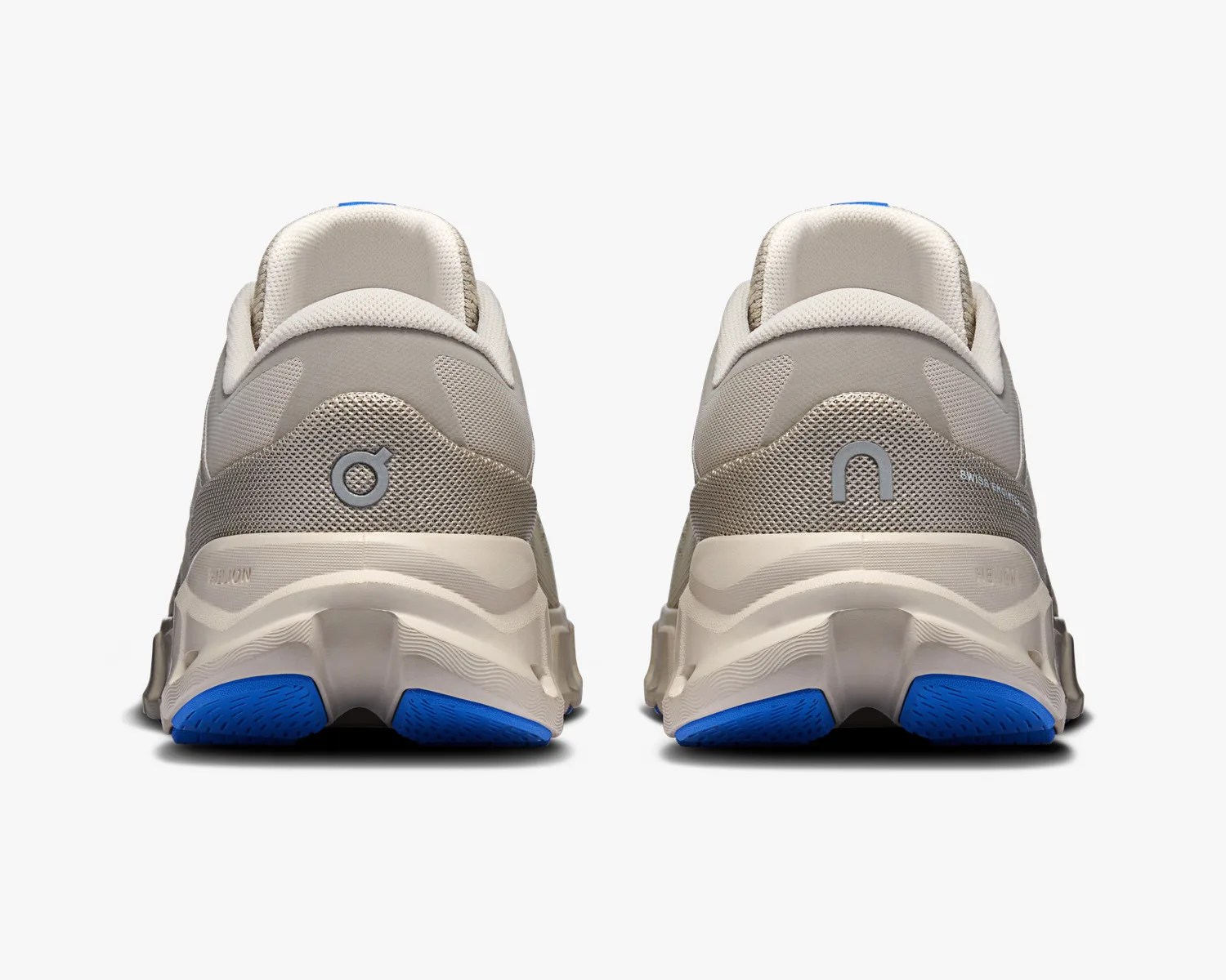 Pair of beige and gray athletic shoes with blue rubber soles shown from the back.