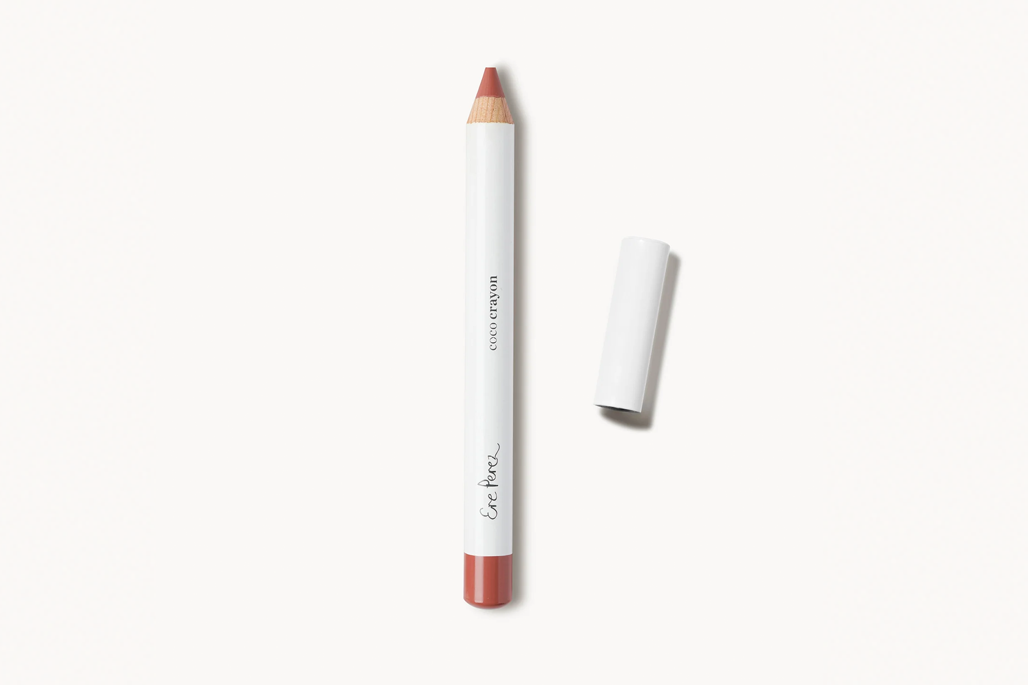 Ere Perez Coco Crayon lip pencil in a terra cotta color, with its cap removed.