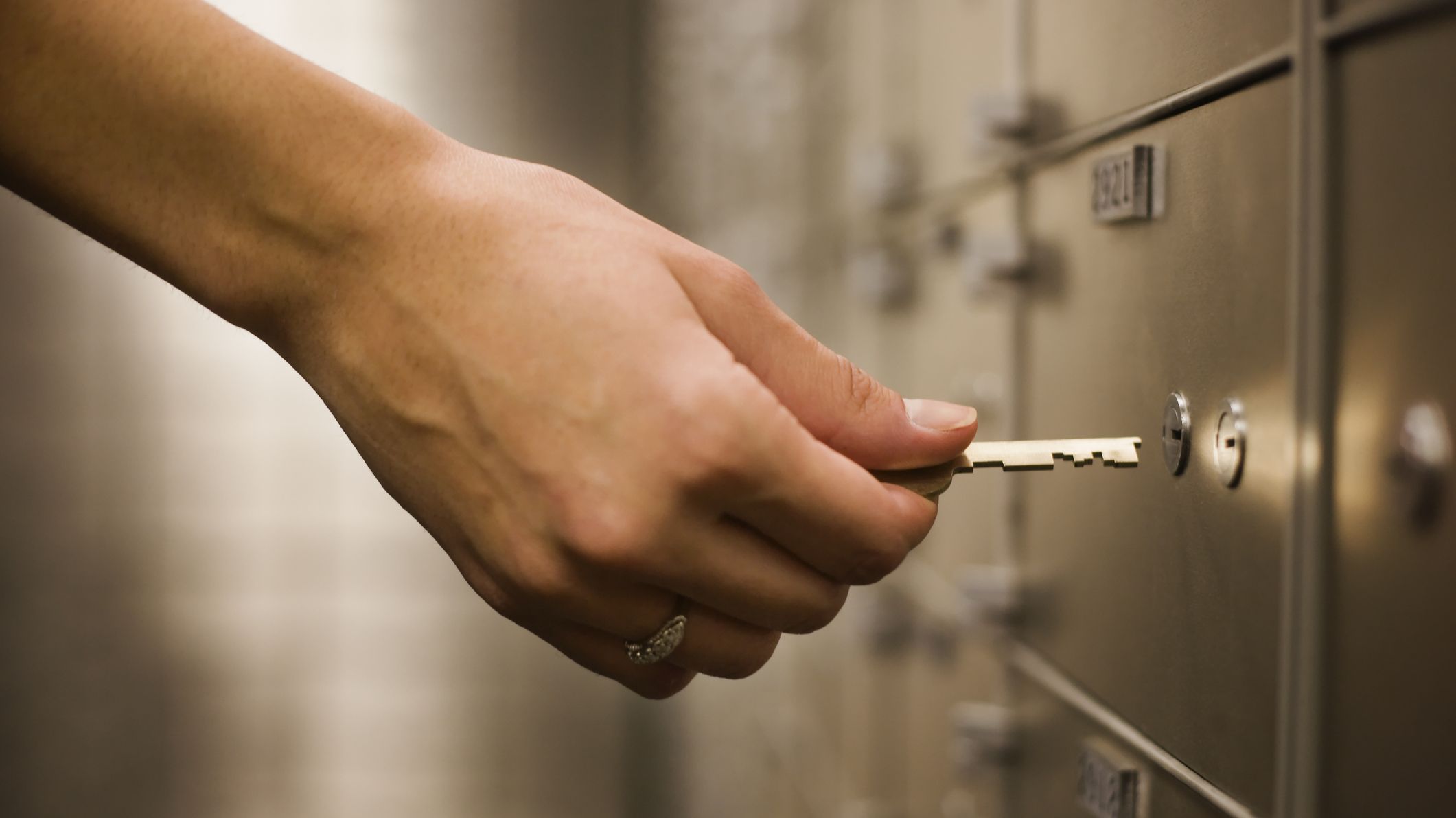 Woman's hand holding key to safety deposit box - stock photo