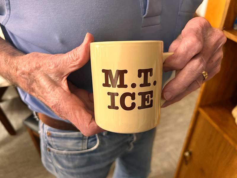 Jack Magnusson holds an old mug with the name of his now-defunct ice business printed on it. | Rett Nelson, EastIdahoNews.com