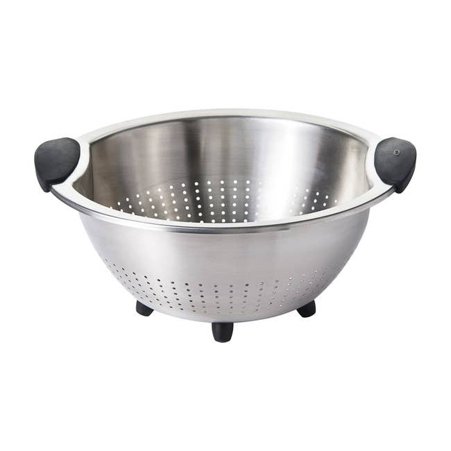 Stainless steel colander with black rubber handles and feet, ideal for draining pasta and washing produce