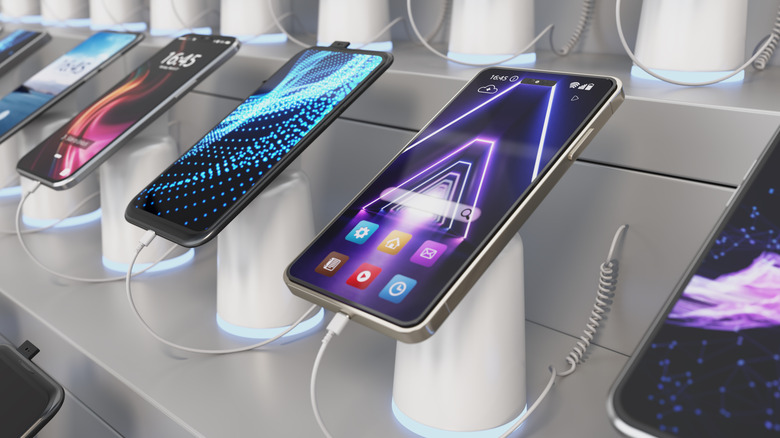 several smartphones on a shelf in a store, waiting to be purchased