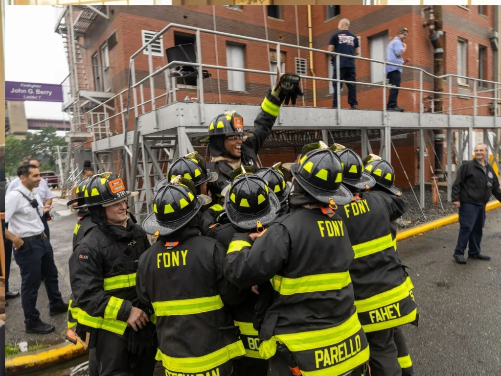 FDNY firefighters lift a jubilant Jayson into the air after Dasia accepts his firefighter proposal.