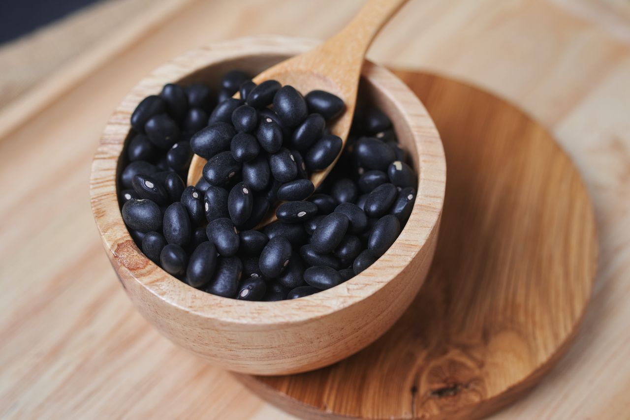 A wooden cup of black bean on the table