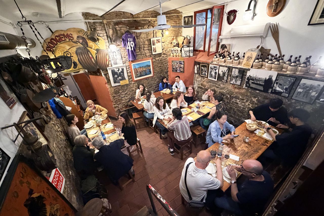 A cozy restaurant interior with people seated at tables enjoying their meals surrounded by stone walls and framed pictures
