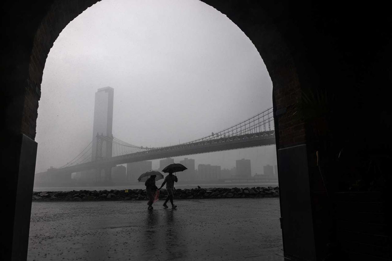 People walk through the rain in the Dumbo neighborhood in Brooklyn as severe storms move through the New York area on July 21, 2026 in New York City. New York City is under a flood watch until 2 am as the storms impact both New Jersey and New York.