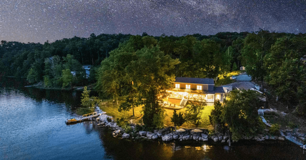An aerial view of a lakefront vacation rental in Kentucky with vibrant stars twinkling overhead.