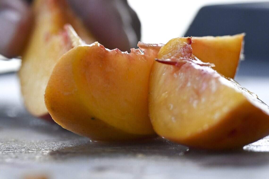Derek Ikeda slices peaches for visitors to sample during an event organized by the California Museum at Ikeda’s in Auburn on Sunday, July 19, 2026. Ikeda’s was recently named the #1 best pie shop in America according to USA Today.