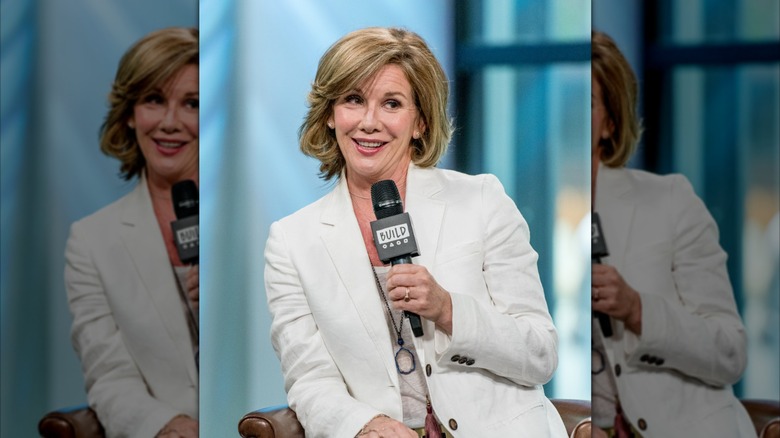Melissa Gilbert speaks into a microphone wearing a white blazer