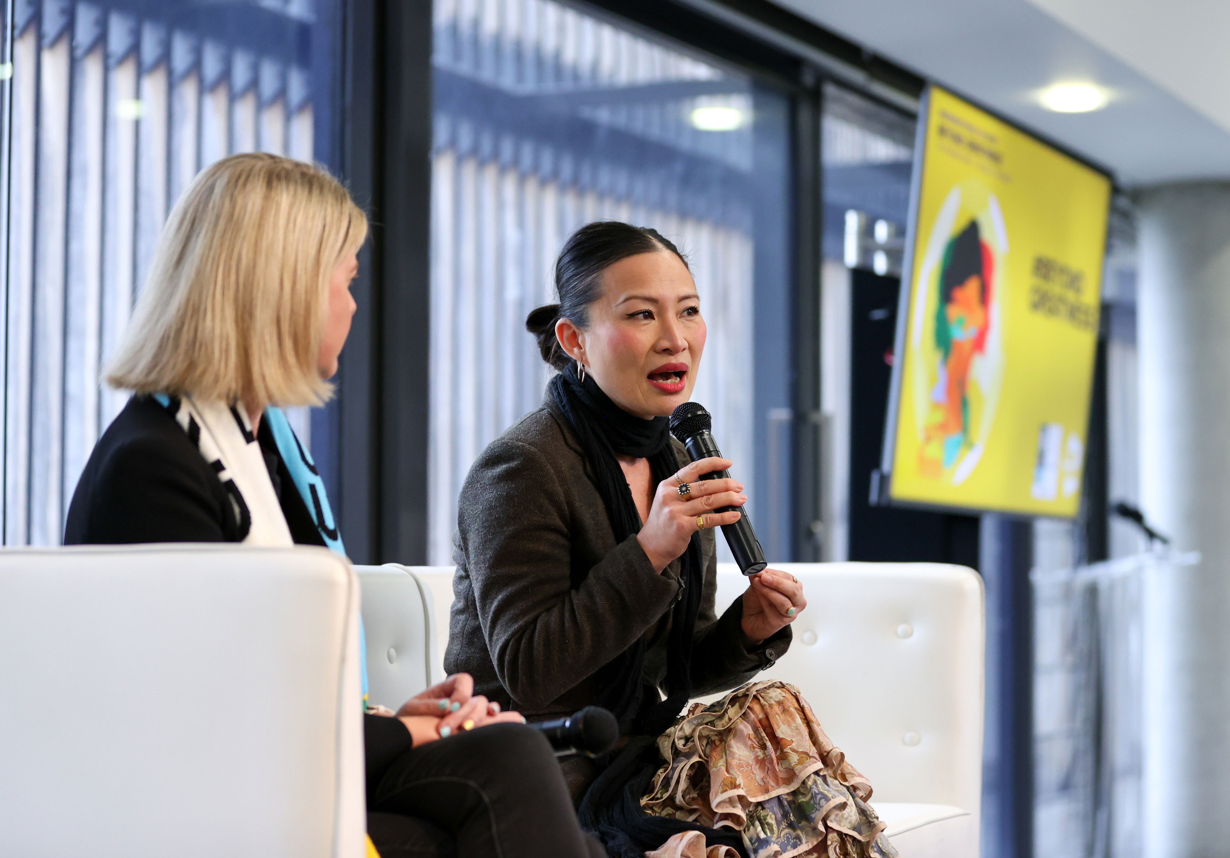 Poh Ling Yeow, a TV Presenter, Author and Visual Artist, speaking into a microphone while sitting on a white couch.