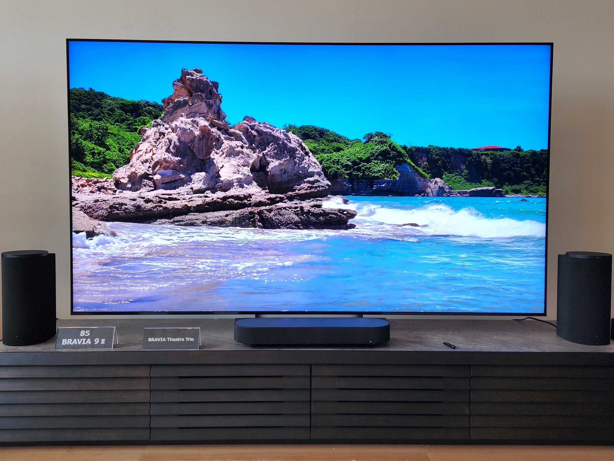 A Sony Bravia 9 II True RGB TV on a media console displaying an image of a rocky shore.