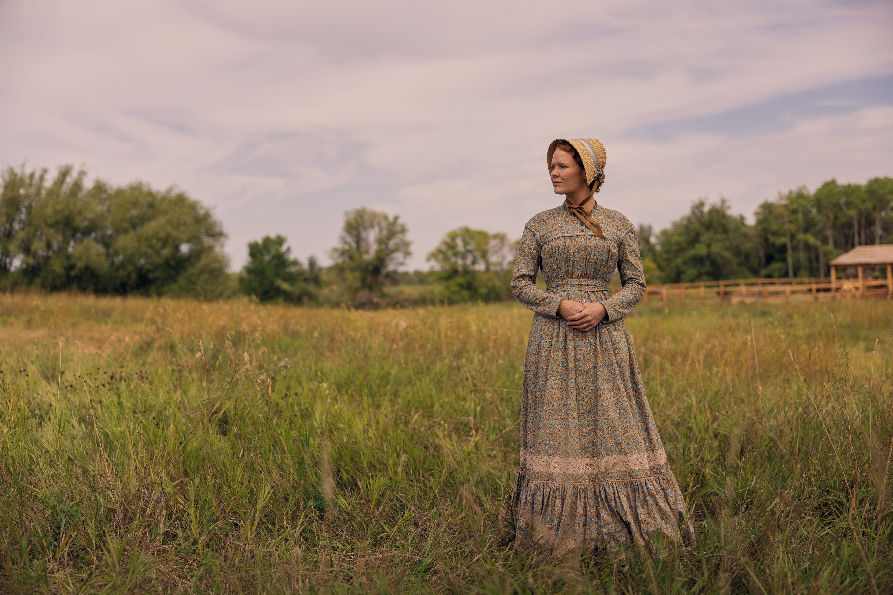 Crosby Fitzgerald as Caroline Ingalls stands in the prairie's long grass