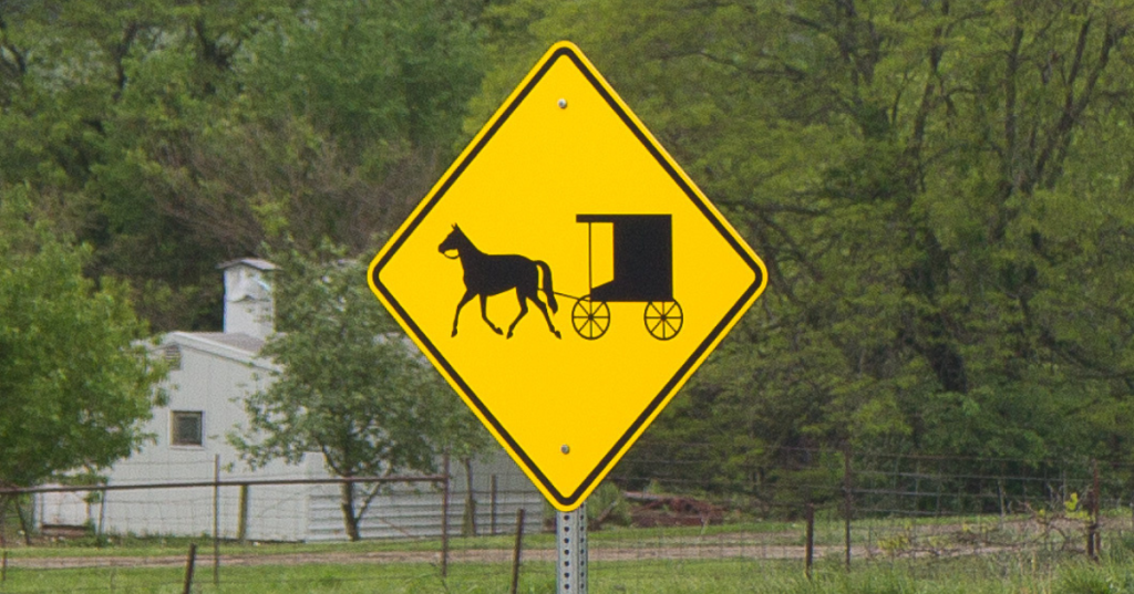 a yellow road sign warning cars about horse-drawn buggies in amish country in iowa