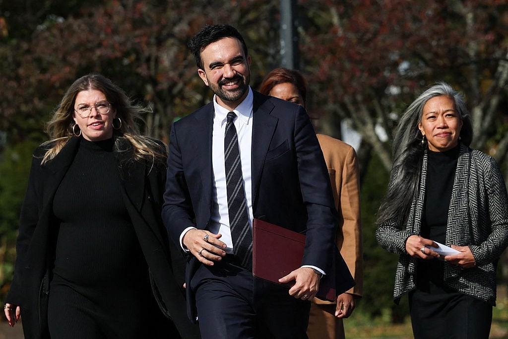 A group of people walking together, dressed in formal business attire, smiling outdoors