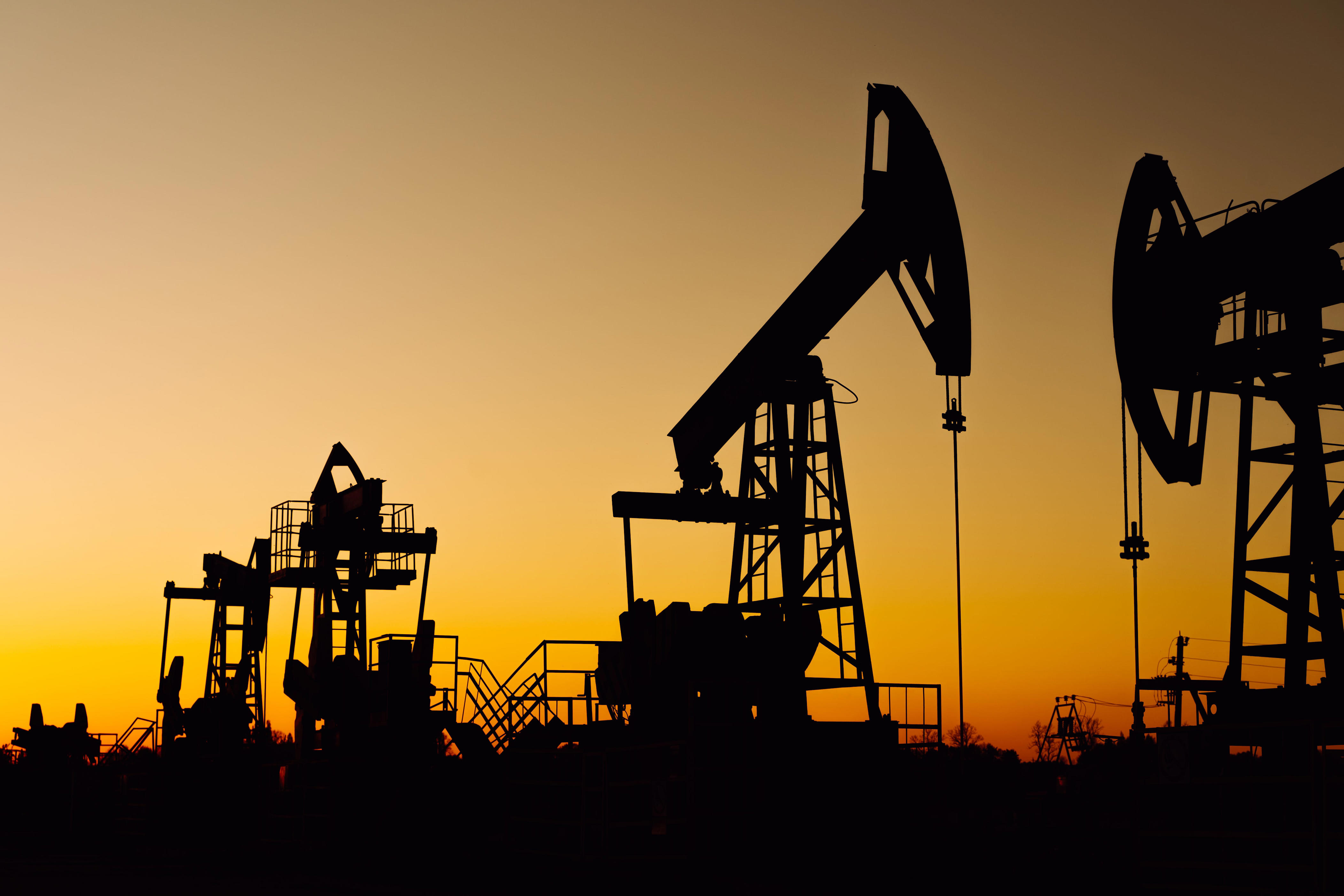 Silhouette of oil rigs working during sunset