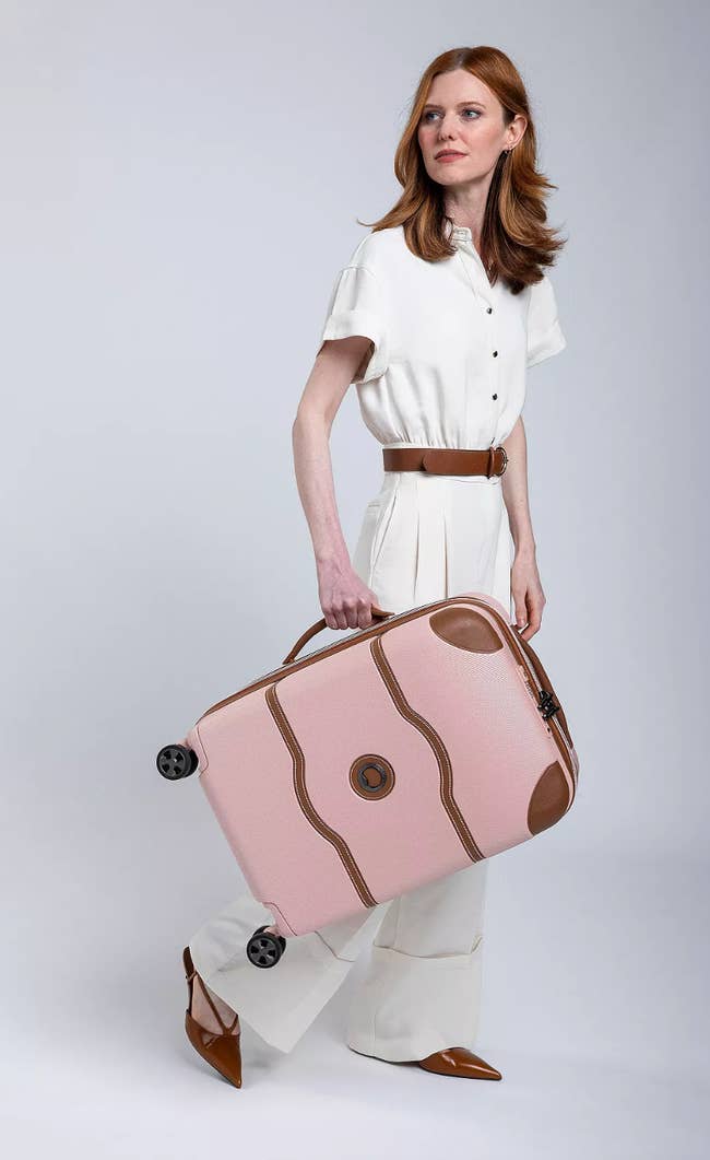 Person in a stylish white outfit holds a chic suitcase, showcasing luggage in a shopping context