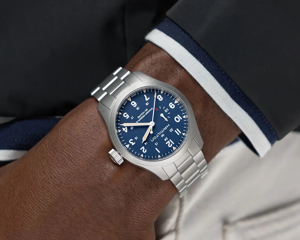 Silver Hamilton wristwatch with a blue dial and white numerals worn on a wrist.