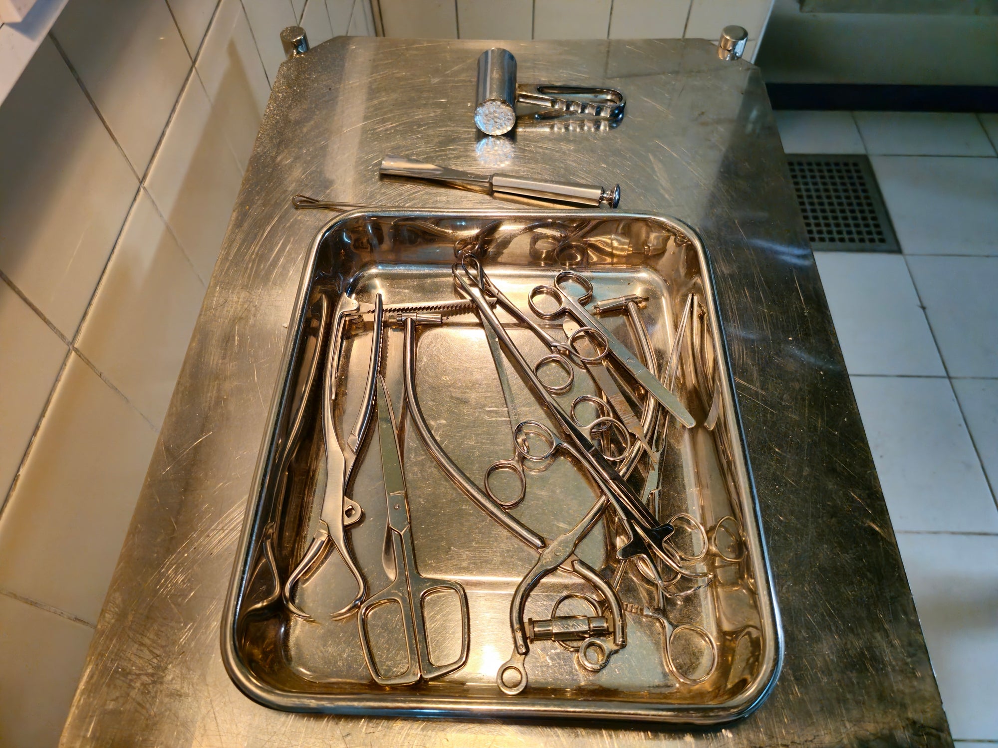Surgical instruments in a metal tray on a table, ready for use in a medical setting