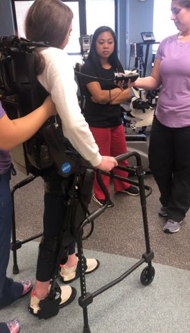 A person using a walker assisted by others in a clinical setting