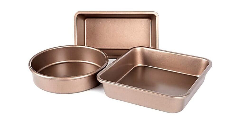 Three nonstick baking pans in different shapes—one rectangle, one round, and one square—are elegantly displayed on a white background.