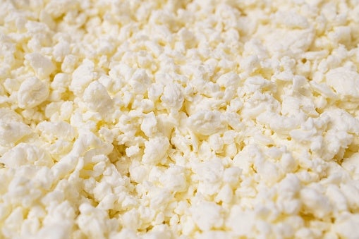 Close-up of crumbled ricotta cheese, showing its soft, textured appearance