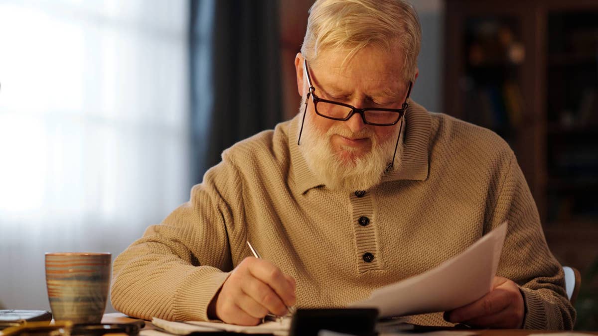 retired-man-with-documents-writing-notes-at-home