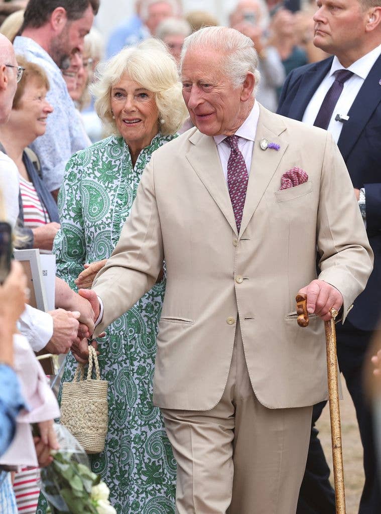 Queen Camilla and King Charles III smile and greet royal fans