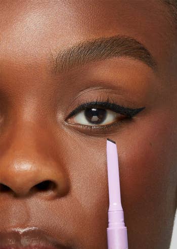 Close-up of a person applying Tarte's Deja Vu eyeliner in black