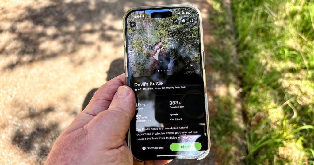 A hand holding a phone displaying the AllTrails route for the Devil's Kettle hike in Minnesota.