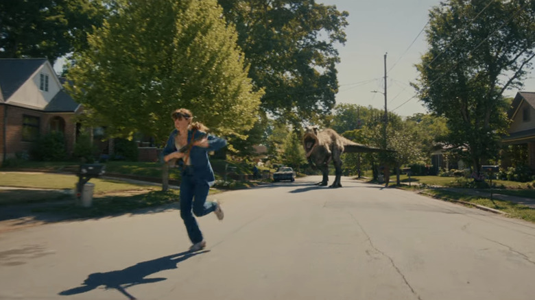 Anne Hathaway's Denise Platt runs from a T.Rex on a suburban street in The End of Oak Street