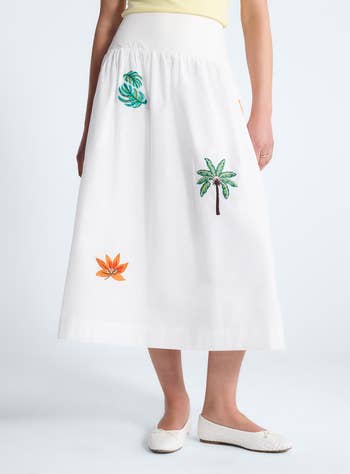 White midi skirt with embroidered tropical leaf designs, paired with a yellow top and white flats