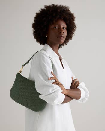 Person in a white shirt models a stylish woven handbag, showcasing a fashion accessory for a shopping article