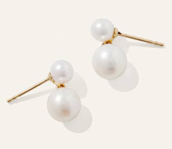 Elegant pearl stud earrings with double pearl design, featuring a smaller and larger pearl on gold posts