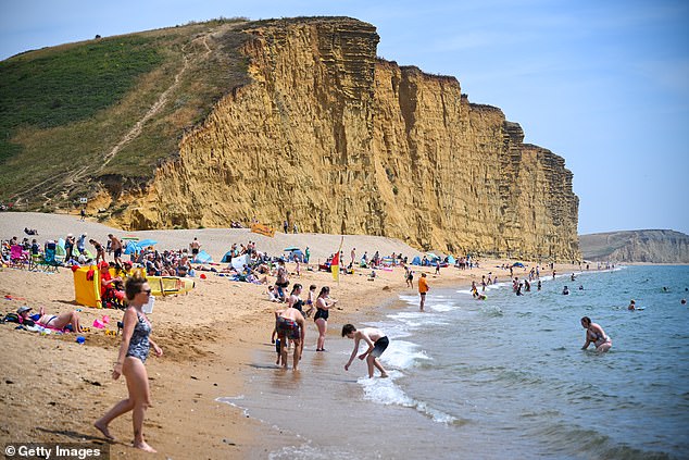 Visitors enjoy the hot weather at East Cliff beach in West Bay, Dorset, yesterday afternoon
