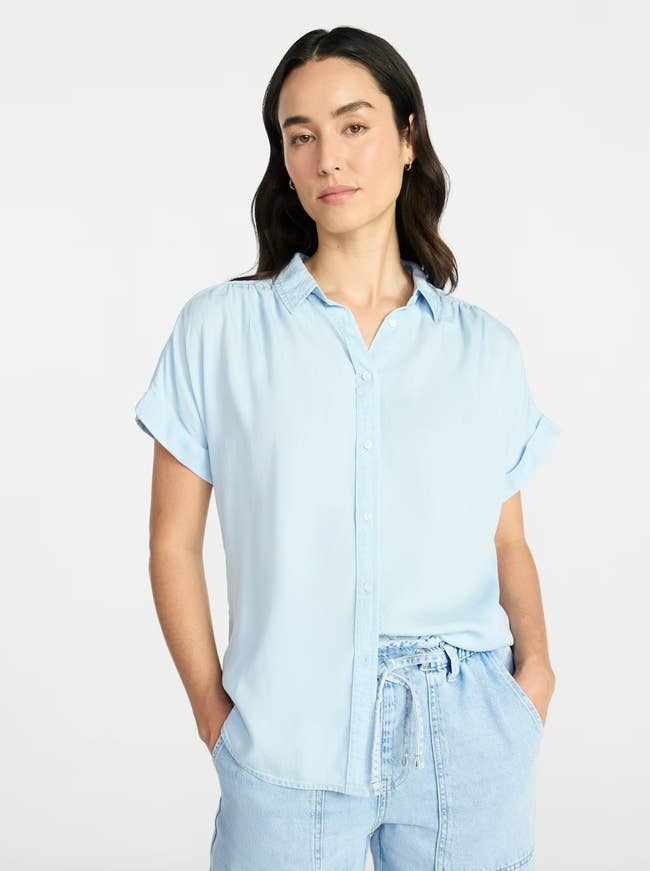 Person wearing a short-sleeve button-up shirt and drawstring shorts, hands in pockets