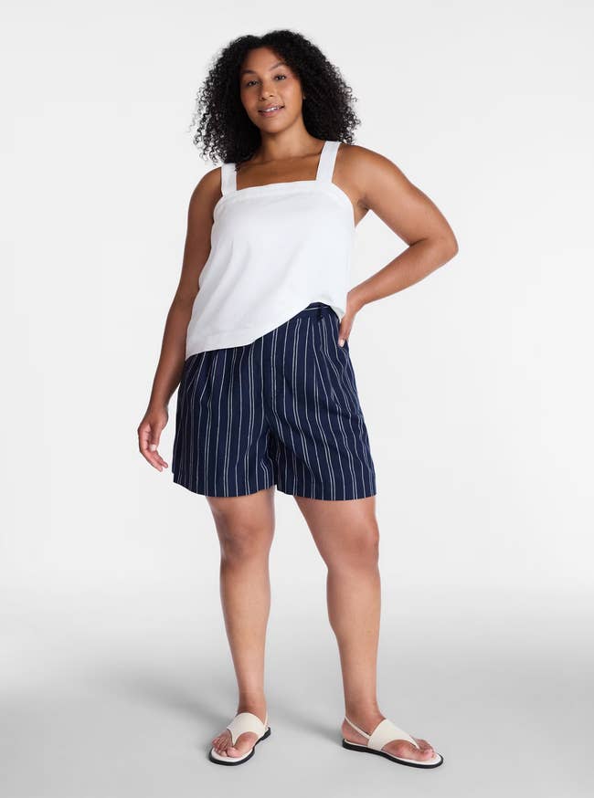 Person in a sleeveless top and striped shorts, standing confidently