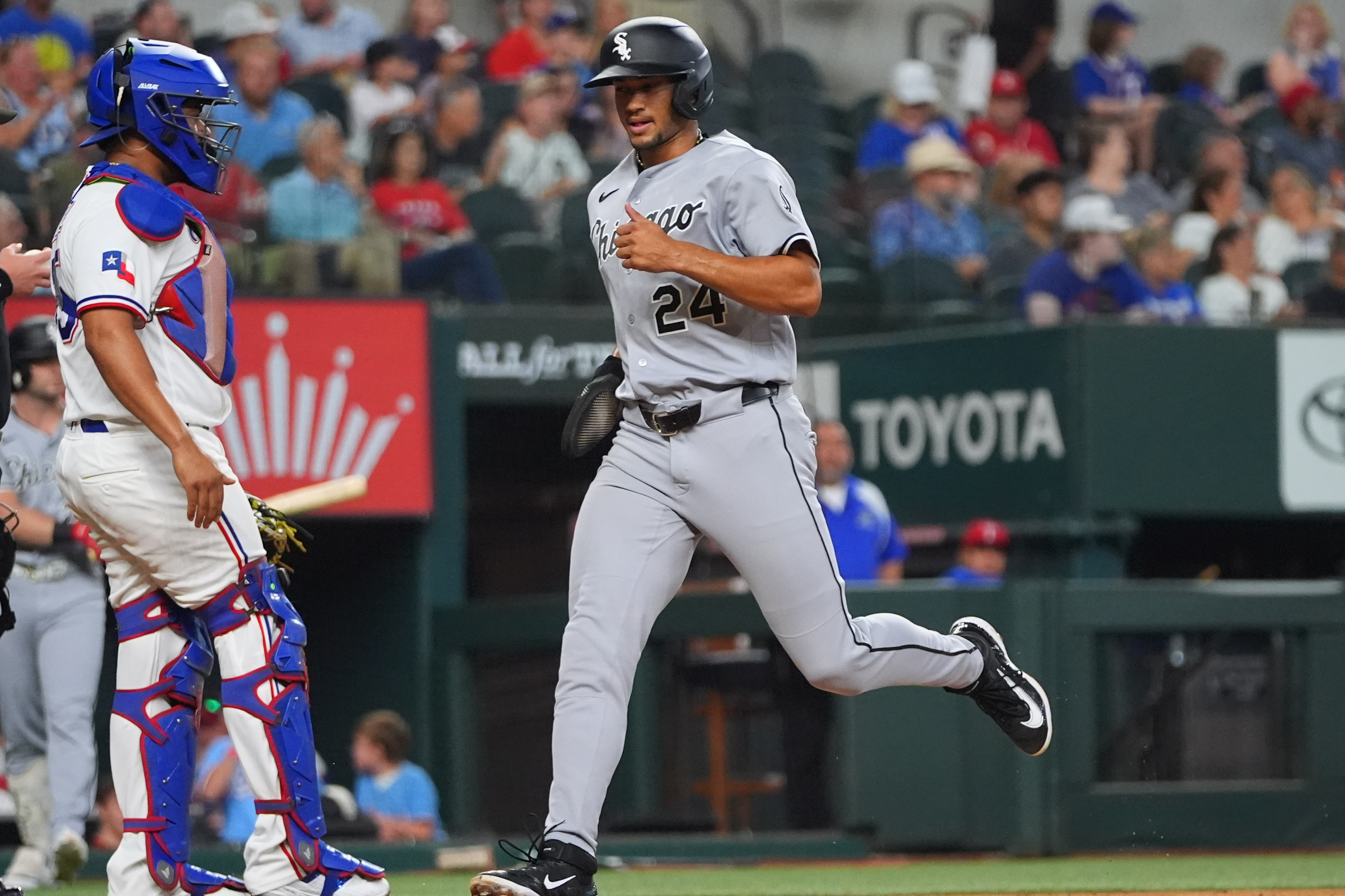 Chicago White Sox's Braden Montgomery (24) scores on a single by teammate Andrew Benintendi past Texas Rangers catcher Elias Díaz during the fourth inning of a baseball game, Wednesday, July 22, 2026, in Arlington, Texas. (AP Photo/LM Otero)