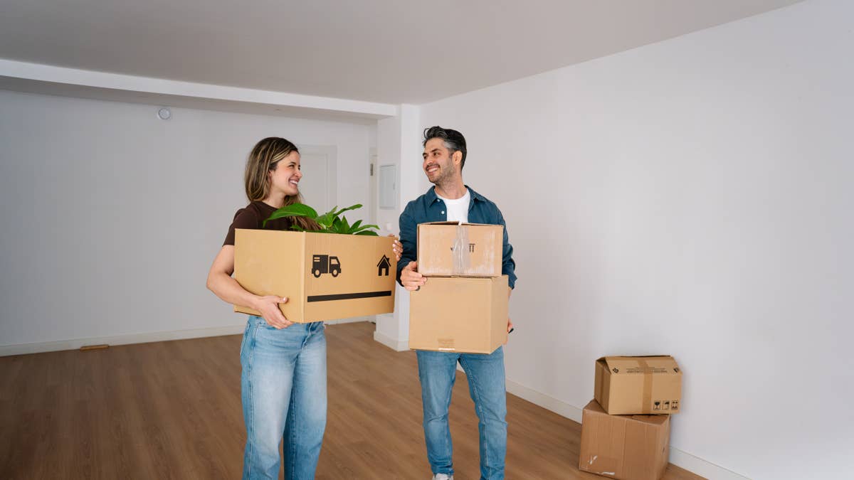 happy-couple-moving-into-new-apartment-with-cardboard-boxes-and-plant-starting-new-life-at-home