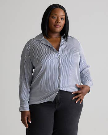 Person models a striped button-up shirt paired with dark pants, showcasing a casual, stylish look suitable for everyday wear