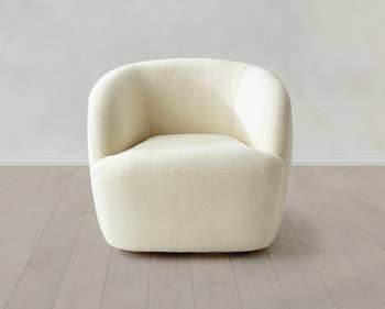 Modern minimalist cream armchair with curved design on wooden floor