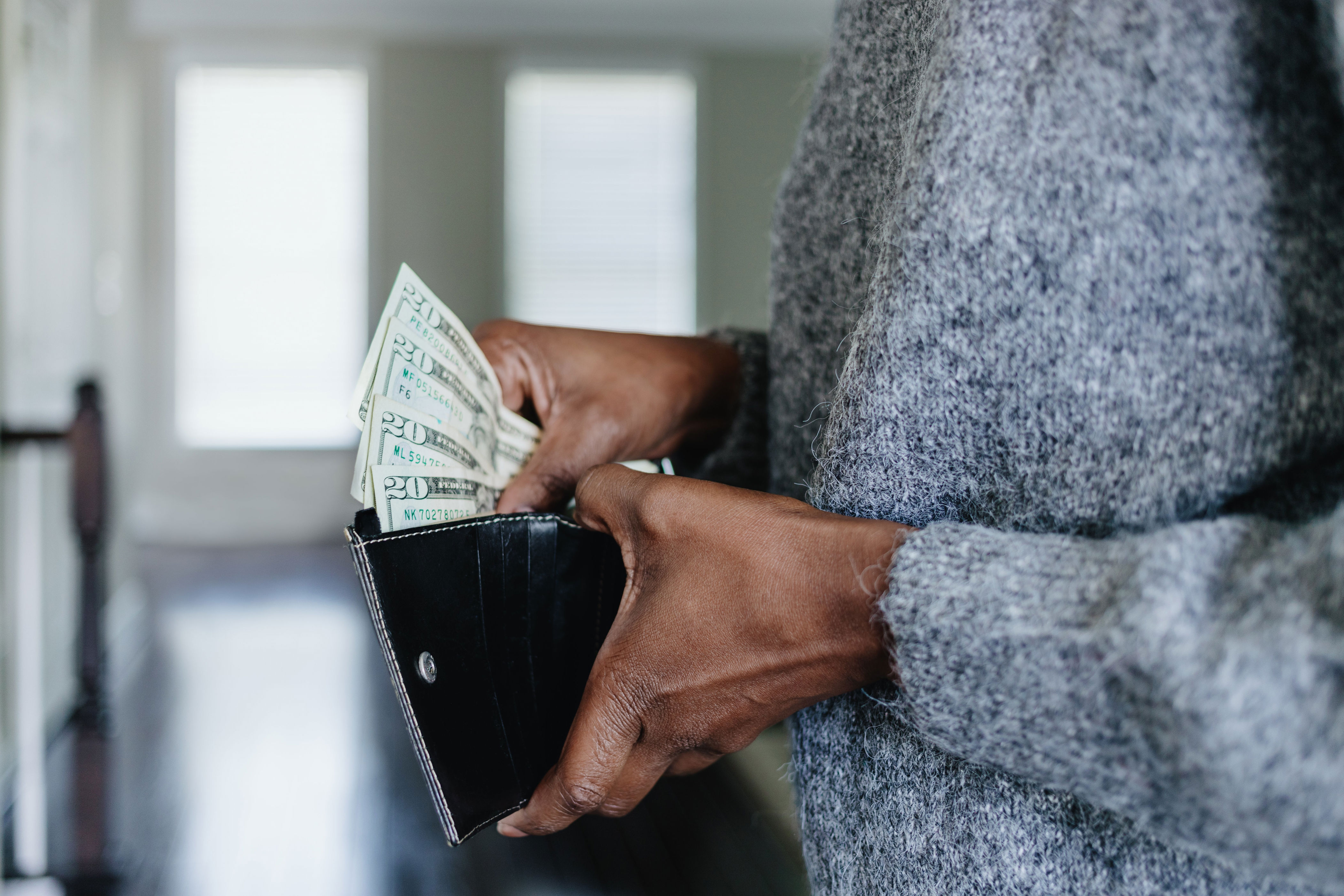 Person holding an open wallet with visible paper money, showcasing financial transaction or budgeting