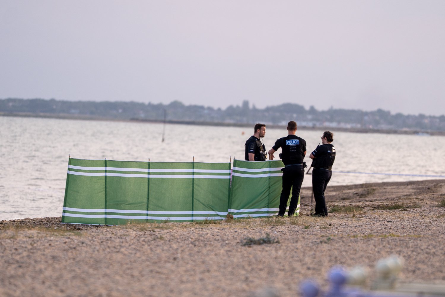 Police on beach standing by wind break