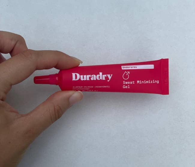 Hand holds a tube of Duradry Sweat Minimizing Gel, designed for underarms, highlighting its usage and packaging for a shopping context