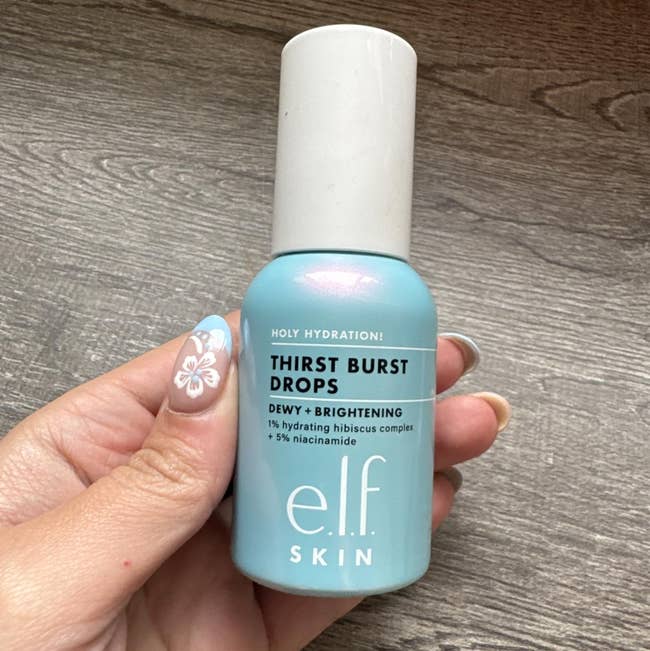 A person holding a bottle of e.l.f. Skin Thirst Burst Drops, a hydrating and brightening skincare product