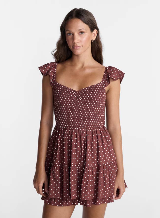 A person in a polka dot summer romper with ruffled cap sleeves and a flowy skirt