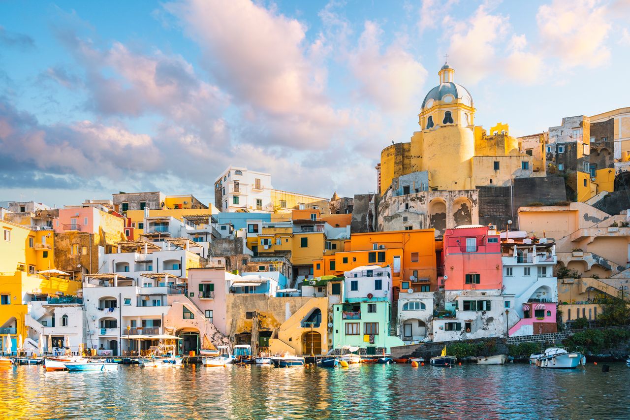 A picturesque view of Procida Italy showing colorful houses and a church dome by the waters edge