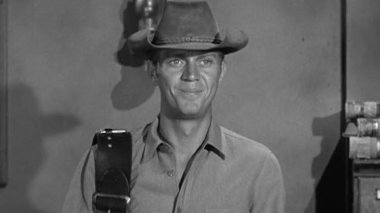 Steve McQueen's Josh Randall smiles as he stands in a sheriff's office in Wanted Dead or Alive