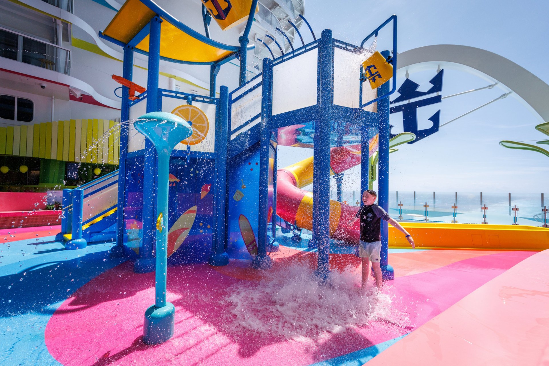 An outdoor playground on Legend of the Seas Royal Caribbean cruise ship. A young boy is playing in the water spraying from the slide.