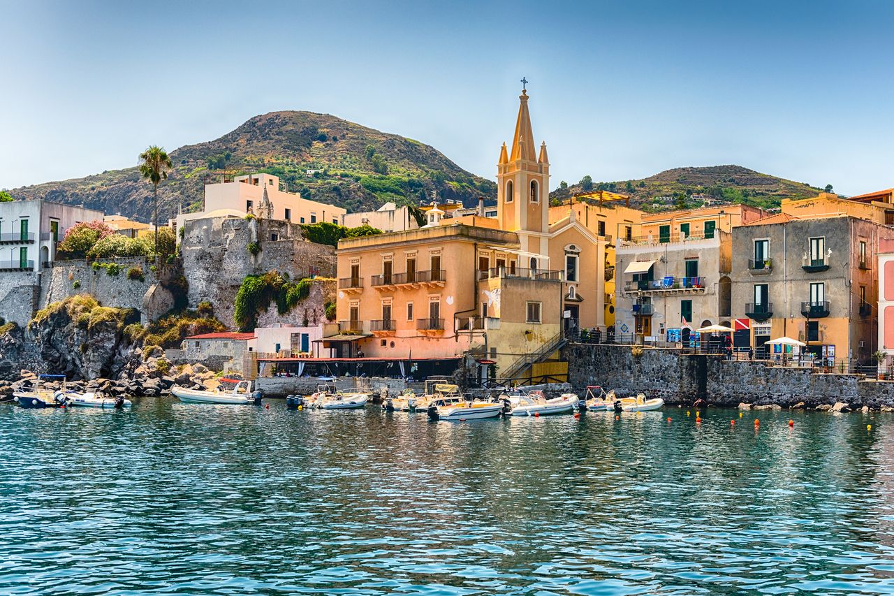 Waterfront view of buildings along the coast with a church and hill in the background